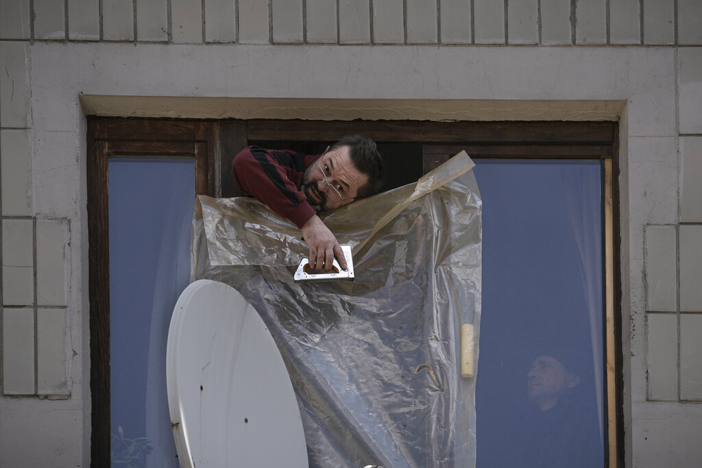People put up plastic sheets to cover the broken windows of their apartments after parts of a Russian missile, shot down by Ukrainian air defense, landed on an apartment block , according to authorities, in Kyiv, Ukraine, Thursday, March 17, 2022. Russian forces destroyed a theater in Mariupol where hundreds of people were sheltering Wednesday and rained fire on other cities, Ukrainian authorities said, even as the two sides projected optimism over efforts to negotiate an end to the fighting. (AP Photo/Vadim Ghirda)